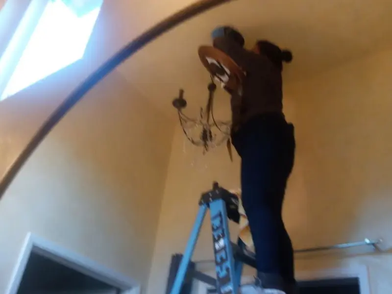 Electrician installing a chandelier in a Brooktrails residence